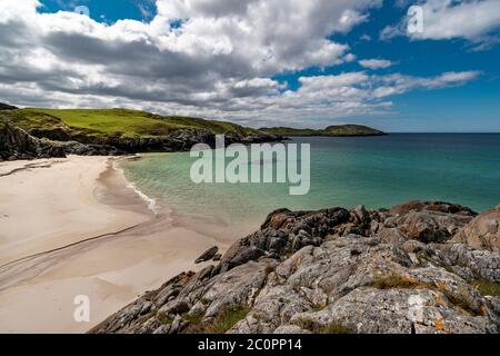 ACHMELVICH BAY UND STRAND SUTHERLAND HIGHLANDS SCHOTTLAND EIN BLAUER HIMMEL MIT WOLKEN DER WEISSE SAND UND DIE VIELEN FARBEN DES MEERES Stockfoto