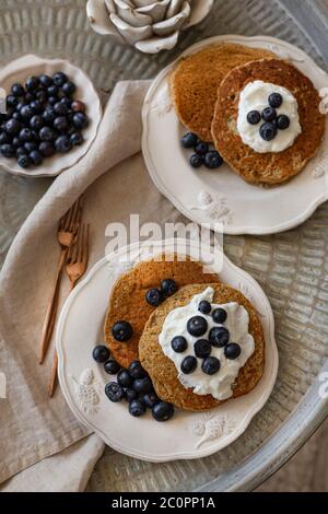 Topview Bild von Haferflocken Pfannkuchen serviert in zwei Keramik-Platten, gekrönt mit Joghurt und Heidelbeeren. Stockfoto