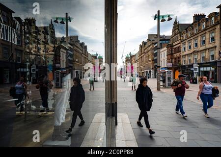 Glasgow, Schottland, Großbritannien. 12. Juni 2020. Blick auf die Menschen in der Buchanan Street Fußgängerzone Einkaufszone spiegelt sich in Schaufenster. Obwohl die Geschäfte in England nächste Woche wieder eröffnet werden können, wird in Schottland die Sperre nicht so schnell entspannt, da noch mehrere Wochen Restriktionen zu erwarten sind. Geschäfte und Geschäfte bleiben geschlossen und die Straßen sind sehr ruhig. Iain Masterton/Alamy Live News Stockfoto