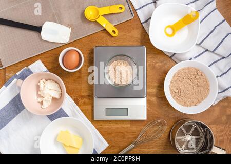 Cookie Zutaten zum Backen mit braunem Zucker im Digitalmaßstab auf Holztisch Stockfoto