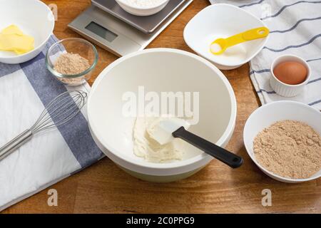 Frischkäse in Rührschüssel mit Keksen auf Holztisch Stockfoto
