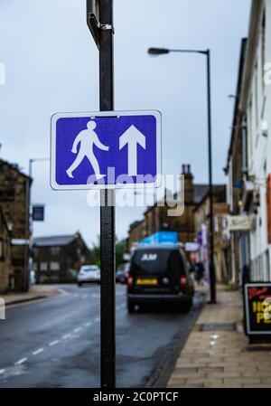 Ein blau-weißes Fußgängerschild, das an einem Pfosten während Covid-19 angebracht ist. Das Schild fordert die Leute auf, in Baildon, Yorkshire, in die gleiche Richtung zu gehen. Stockfoto