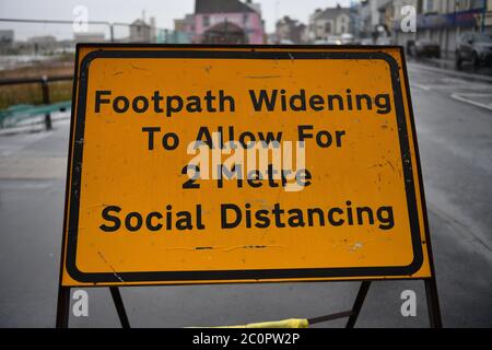 Hartlepool, County Durham - EIN vorübergehendes Straßenschild erzählt der Öffentlichkeit von der Erweiterung des Fußweges, um 2 Meter soziale Distanzierregel in England zu ermöglichen. Stockfoto