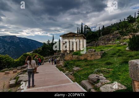 Delphi Town, Phocis / Griechenland. Touristen folgen dem Heiligen Weg an der berühmten archäologischen Stätte von Delphi. Schatz des Gebäudes der Athenen Stockfoto