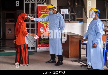 Sleman, YOGYAKARTA, INDONESIEN. Juni 2020. Das Gesundheitspersonal misst die Temperatur der Krankenhausbesucher, indem es sich mit einem Feldschild vor dem Ausbruch des Corona-Virus in Sleman, Yogyakarta, am Freitag, 12. Juni 2020, schützt. Die indonesische Regierung bestätigte, dass sie auf 1,111 Fälle auf 36,406 Coronavirus-positive Fälle anstieg. Quelle: Slamet Riyadi/ZUMA Wire/Alamy Live News Stockfoto