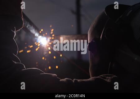 Arbeiter mit Schutzmaske Schweißen Metall und die Produktion von Rauch und Funken. Lichtbogenschweißen Stockfoto