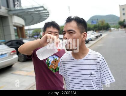 (200612) -- ZHUJI, 12. Juni 2020 (Xinhua) -- EIN Freund hilft Jin Jiangwei (R) beim Wassertrinken in Zhuji, Ostchinas Provinz Zhejiang, 12. Juni 2020. Jin Jiangwei, ein 34-jähriger Dorfbewohner des Dorfes Leshan in der Stadt Zhuji, verlor seine Arme aufgrund eines Unfalls im Alter von fünf Jahren. 2016 eröffneten Jin Jiangwei und sein Bruder einen Online-Shop für den Verkauf von Socken, in dem Jin für die Ladenplanung und den Kundenservice zuständig ist. Nach Jahren der Praxis ist Jin in in der Lage, mit seinen Füßen so schnell zu tippen wie normale Menschen. Der Jahresumsatz des Ladens hat eine Million Yuan (etwa 141,288 US-Dollar) in rec überschritten Stockfoto