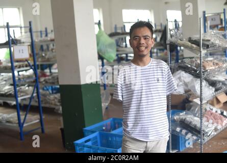 (200612) -- ZHUJI, 12. Juni 2020 (Xinhua) -- Jin Jiangwei wird im Lager seines Online-Shops in Zhuji, Ostchinas Provinz Zhejiang, am 12. Juni 2020 gesehen. Jin Jiangwei, ein 34-jähriger Dorfbewohner des Dorfes Leshan in der Stadt Zhuji, verlor seine Arme aufgrund eines Unfalls im Alter von fünf Jahren. 2016 eröffneten Jin Jiangwei und sein Bruder einen Online-Shop für den Verkauf von Socken, in dem Jin für die Ladenplanung und den Kundenservice zuständig ist. Nach Jahren der Praxis ist Jin in in der Lage, mit seinen Füßen so schnell zu tippen wie normale Menschen. Der Jahresumsatz des Ladens hat eine Million Yuan (etwa 141,288 US-D überschritten Stockfoto