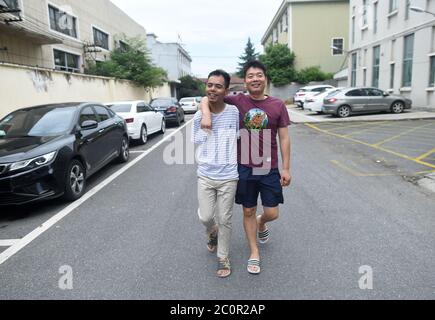 (200612) -- ZHUJI, 12. Juni 2020 (Xinhua) -- Jin Jiangwei (L) geht mit seinem Freund auf der Straße in Zhuji, Ostchinas Provinz Zhejiang, 12. Juni 2020. Jin Jiangwei, ein 34-jähriger Dorfbewohner des Dorfes Leshan in der Stadt Zhuji, verlor seine Arme aufgrund eines Unfalls im Alter von fünf Jahren. 2016 eröffneten Jin Jiangwei und sein Bruder einen Online-Shop für den Verkauf von Socken, in dem Jin für die Ladenplanung und den Kundenservice verantwortlich war. Nach Jahren der Praxis ist Jin in in der Lage, mit seinen Füßen so schnell zu tippen wie normale Menschen. Der Jahresumsatz des Ladens hat eine Million Yuan (etwa 141,288 US-Dollar Stockfoto