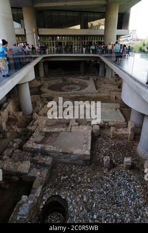 Athen, Attika / Griechenland. Außenansicht des modernen Akropolis-Museums in Athen. Besucher schauen auf die antiken Ruinen vor dem Museum. Stockfoto