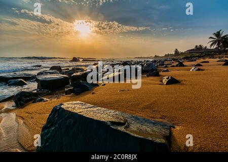 Strand mit rotem Sand und schwarzen Felsen mit einem schönen Sandset in Congo Town, Monrovia, Liberia Stockfoto