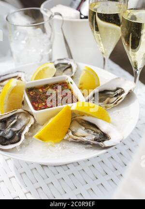 Frische Austern Schale mit Zitrone und Gläser Champagner Stockfoto