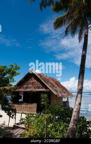 Einsame Nipa-Hütte auf Stelzen mit Palme an einem schönen Strand direkt am Meer Stockfoto