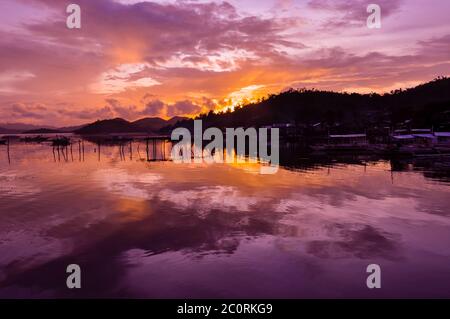 Pretty Pink orange Sky Wolkengebilde über eine Insel mit Reflexion bei Sonnenuntergang auf der Insel Coron Stockfoto