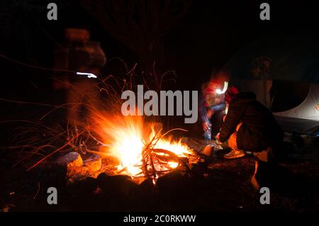 Wanderer versammelten sich rund um ein Lagerfeuer am Abend mit Langzeitbelichtung geschossen Stockfoto