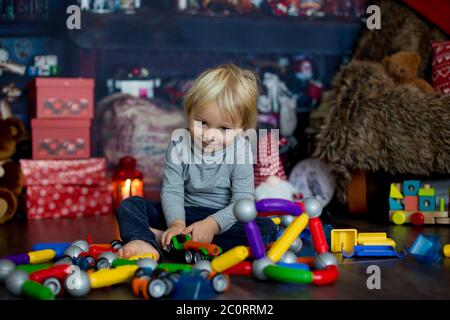 Sweet blonde Kleinkind Junge, spielen mit Kunststoff-Konstruktion, so dass verschiedene Formen, weihnachtsdekoration um ihn herum Stockfoto