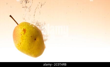 Frische Birne mit grün-roten Seiten fällt ins Wasser klopft Spritzer aus Stockfoto