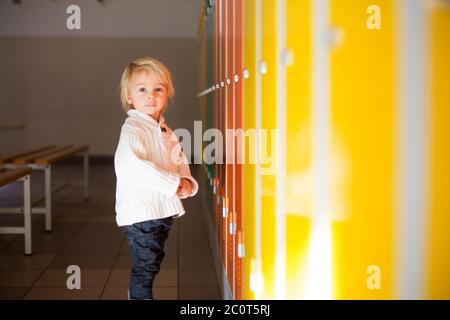 Sweet blonde Kleinkind Junge vor einem Spinde im Kindergarten oder Schulflur, Winterzeit Stockfoto