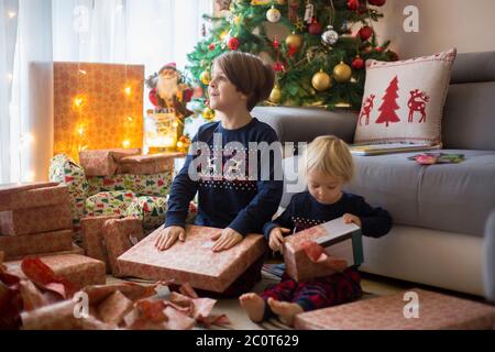 Glückliche Kinder, Jungen, Eröffnung Geschenke am weihnachtstag, in Pyjamas gekleidet Stockfoto