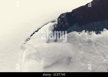 Mann kratzt Schnee und Eis vom Autofenster Stockfoto