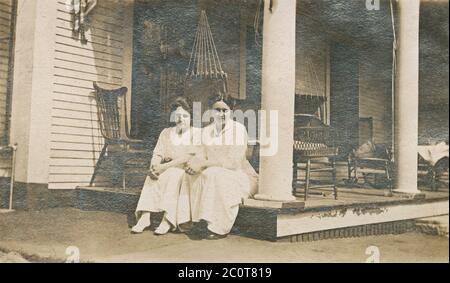 Antike Fotografie April 1913, zwei Frauen sitzen auf der Veranda draußen. Genaue Lage unbekannt, wahrscheinlich New Hampshire oder Massachusetts. QUELLE: ORIGINALFOTO Stockfoto