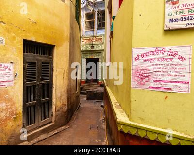 Varanasi, Uttar Pradesh, Indien - Februar 2015: Eine schmale Gasse mit gelben Wänden von alten Häusern und einem verzierten Eingang in der alten Stadt. Stockfoto