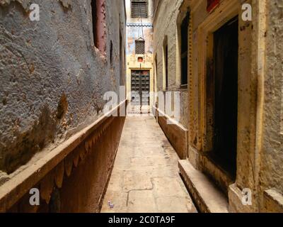 Varanasi, Uttar Pradesh, Indien - Februar 2015: Eine schmale Gasse, die zu einer schönen, kunstvollen Holztür eines alten Hauses in der alten Stadt führt. Stockfoto