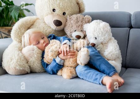 Blonde Kleinkind Junge, schlafen mit vielen Teddybären am Nachmittag auf dem Sofa Stockfoto