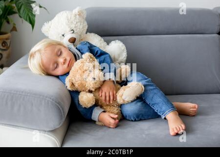 Blonde Kleinkind Junge, schlafen mit vielen Teddybären am Nachmittag auf dem Sofa Stockfoto