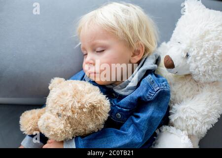 Blonde Kleinkind Junge, schlafen mit vielen Teddybären am Nachmittag auf dem Sofa Stockfoto