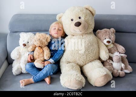 Blonde Kleinkind Junge, schlafen mit vielen Teddybären am Nachmittag auf dem Sofa Stockfoto