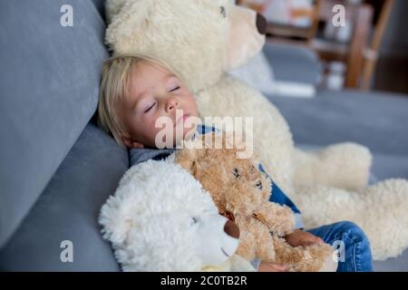 Blonde Kleinkind Junge, schlafen mit vielen Teddybären am Nachmittag auf dem Sofa Stockfoto