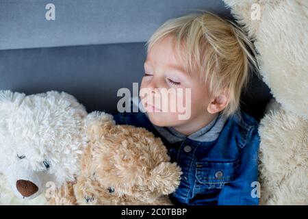 Blonde Kleinkind Junge, schlafen mit vielen Teddybären am Nachmittag auf dem Sofa Stockfoto