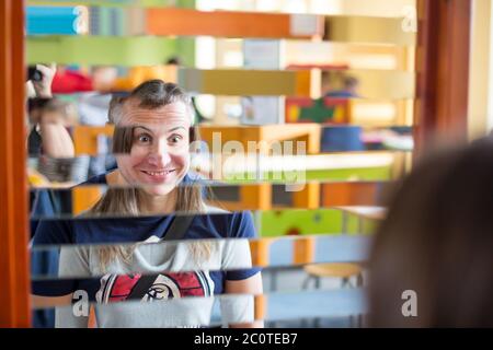 Lustige Doppel-Halbportrait von zwei Erwachsenen, Mann und Frau, die sich in einem Halbspiegel, mit gemischten Gesichtern Stockfoto