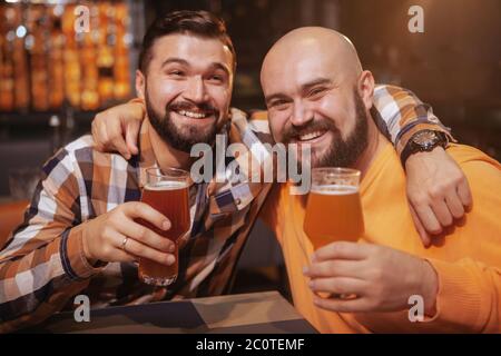 Zwei fröhliche männliche Freunde umarmen, trinken gemeinsam Bier in der Kneipe Stockfoto