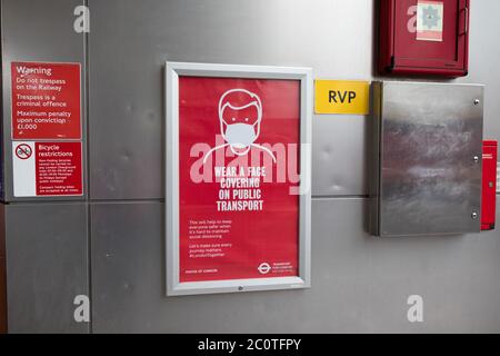 Tragen Sie eine Gesichtsbedeckung auf dem Plakat für öffentliche Verkehrsmittel vor dem Bahnhof Shoreditch High Street, East London Stockfoto