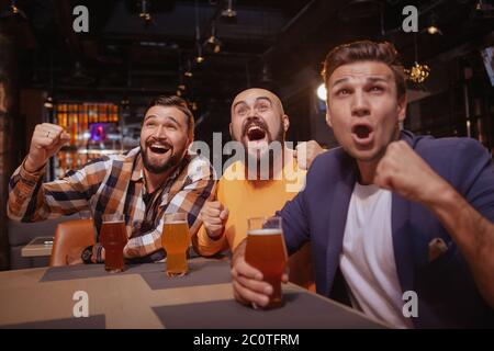 Eine Gruppe von Freunden, die im Bierkneipe Fußballspiele anschauen. Männliche Fußballfans freuen sich und feiern den Sieg ihrer Lieblingsmannschaft Stockfoto