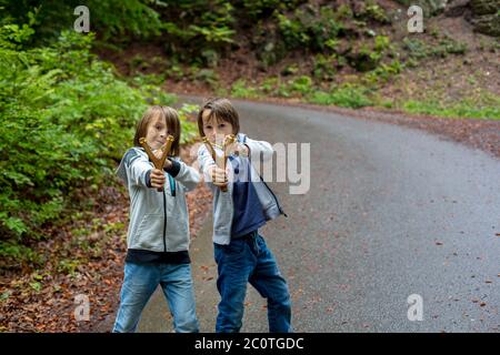 Vorschuljungen, Kinder mit Schleuder im Wald, Schießen auf das Ziel im Wald Stockfoto