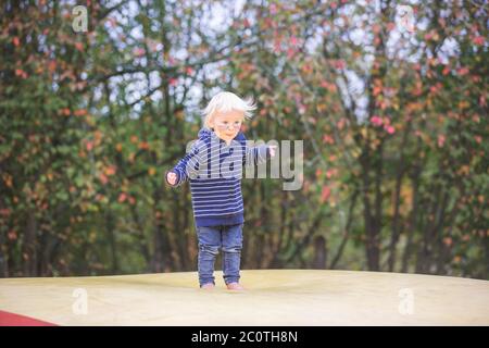 Nettes Kind, Junge, springen auf einem großen Trampolin im Park, Herbstzeit Stockfoto