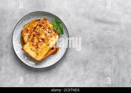 Französische Toasts mit Honigsirup auf dem Teller, Draufsicht, Kopierraum. Gebratener französischer Toast zum Frühstück. Stockfoto