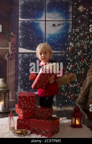 Schöne Kleinkind Junge, Eröffnung Geschenke in der Weihnachtsnacht, heimlich schleichen in das Zimmer nach dem Weihnachtsmann Stockfoto