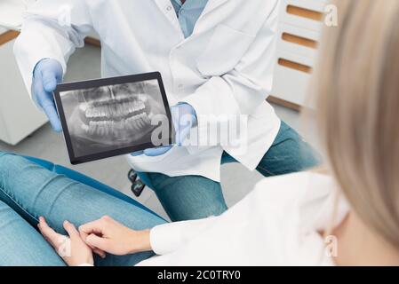 Zahnärztliche Beratung in der Klinik. Zahnarzt zeigt Zähne Röntgen auf digitalen Tablet-Bildschirm Stockfoto