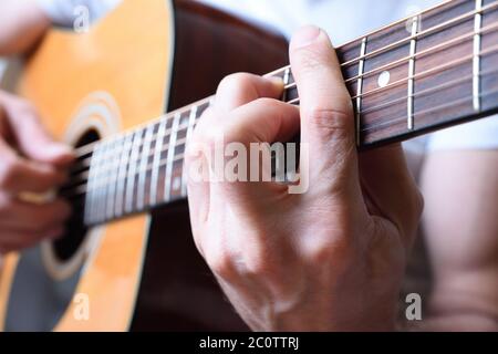 Detail des Mannes spielt akustische Gitarre mit Hand machen Akkord Stockfoto