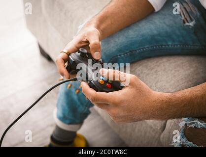 Schönheit männliche Hände mit Joystick. Gamer verwendet kabelgebundene Gamepad spielen Computerspiele. Nahaufnahme. Home Entertainment-Konzept. Getöntes Bild Stockfoto