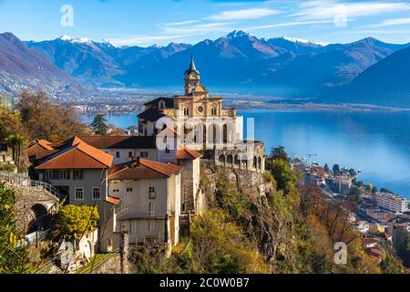 Atemberaubende Nahaufnahme Panoramablick auf die Kirche Madonna del Sasso über Locarno Stadt mit Lago Maggiore, schneebedeckten Schweizer Alpen Berggipfel und blauen Himmel Stockfoto