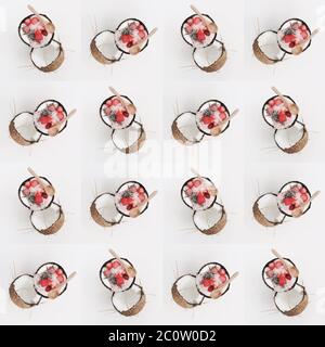Frische Bio-Beeren, innen reife Kokosnüsse. Draufsicht. Pop Art Design, kreatives Sommerkonzept. Hälfte Kokosnuss in minimaler flacher Lay-Form. Nahtlos Stockfoto