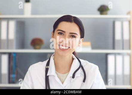 Portrait der schönen jungen Ärztin Blick auf die Kamera im medizinischen Büro, mit Online-Beratung mit Patienten Stockfoto
