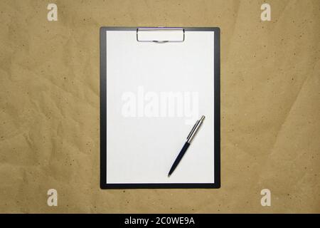 Ein Tablett mit einem weißen Blatt im A4-Format mit Stift auf einem beigen Bastelpapier. Konzept der Analyse, des Studiums, der aufmerksamen Arbeit. Stock Foto mit leerem Platz für Ihren Text und Design. Stockfoto