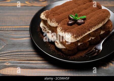 Klassisches Tiramisu Dessert auf Keramikplatte auf Holzhintergrund Stockfoto
