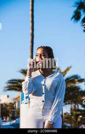 Junge afroamerikanische Frau mit geflochtenen Haaren, die mit ihrem Telefon spricht Stockfoto